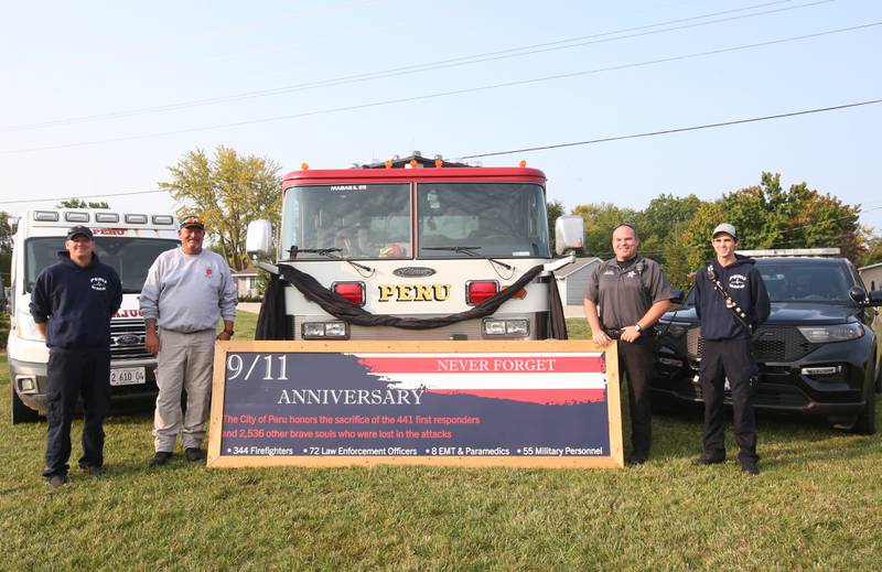 (From left) Peru paramedic John Klag, Peru Fire Chief Jeff King, Peru Community Service officer Blake Frund and Peru EMS coordinator Brent Hanson pose next to a 9/11 anniversary memorial sign at the Roundabout on Wednesday, Sept. 11, 2024 at the roundabout in Peru.