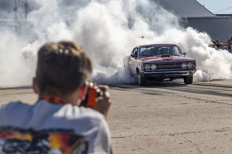 Dane Garrett of Albuquerque takes aim with a camera Monday, June 10, 2024 as a car lights ‘em up on the strip during the burn-out contest.