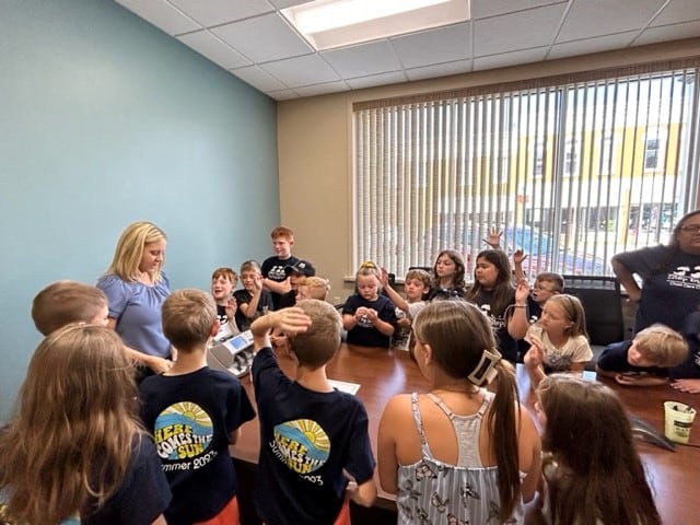 Kids from the Step by Step Summer Camp learn about finances from a Grundy Bank employee.