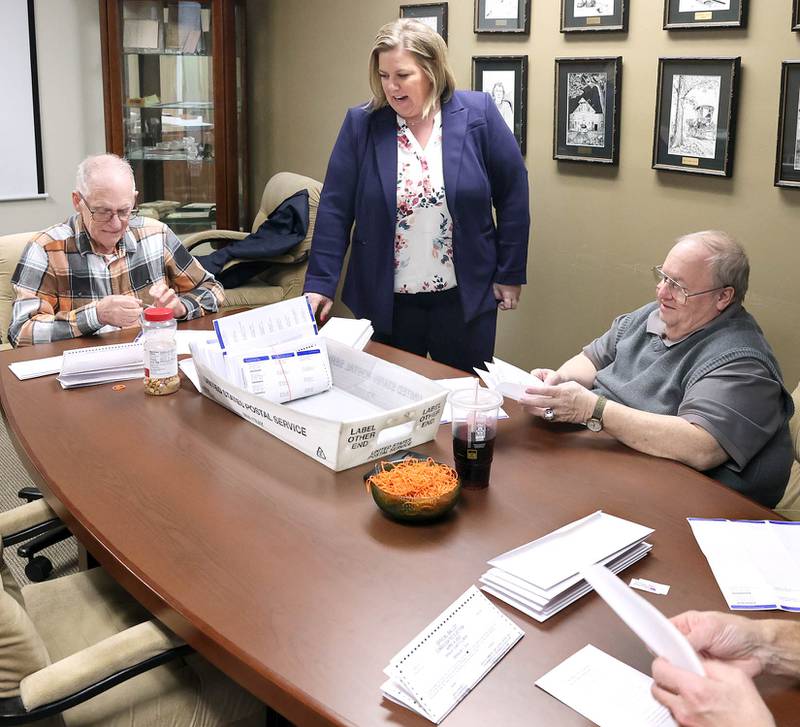 DeKalb County Clerk Tasha Sims visits with election judges Terry Heiland, (left) Steve Nemeth and Brian Frank (right) as they put vote-by-mail ballots in envelopes Wednesday, Feb. 22, 2023, in the DeKalb County Administration Building in Sycamore.