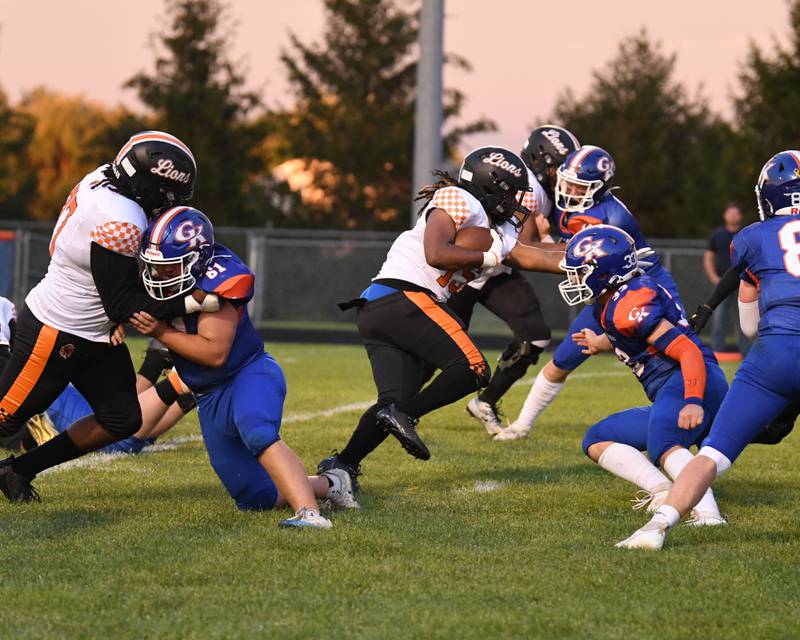 Leo high school Towald Johnson, center, runs the ball before being tackled by Genoa-Kingston players during the game on Friday Aug. 30, 2024, while playing at Genoa-Kingston H