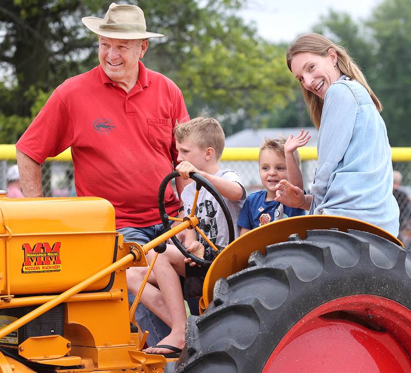 Emory Townsley, 7, (left) and his brother Myles, 3, from Waterman, get some help from their mom Nicole and Dan Cocher, director of the Northern Illinois Steampower Club, as they drive a vintage Minneapolis Moline tractor Saturday, July 16, 2022, at the Waterman Lions Summerfest and Antique Tractor and Truck Show at Waterman Lions Club Park.