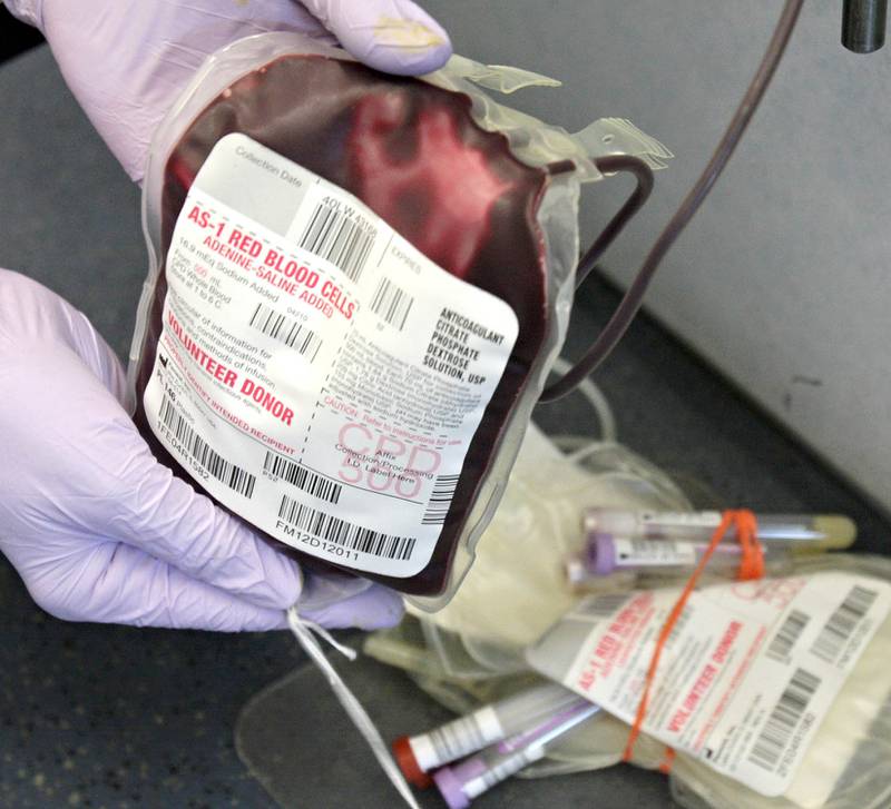 Phlebotomist Joan Falkenhan shakes a blood donation bag to prevent clotting during an American Red Cross blood drive outside the Castle Bank on Greenwood Avenue in DeKalb Thursday, July 12, 2012.