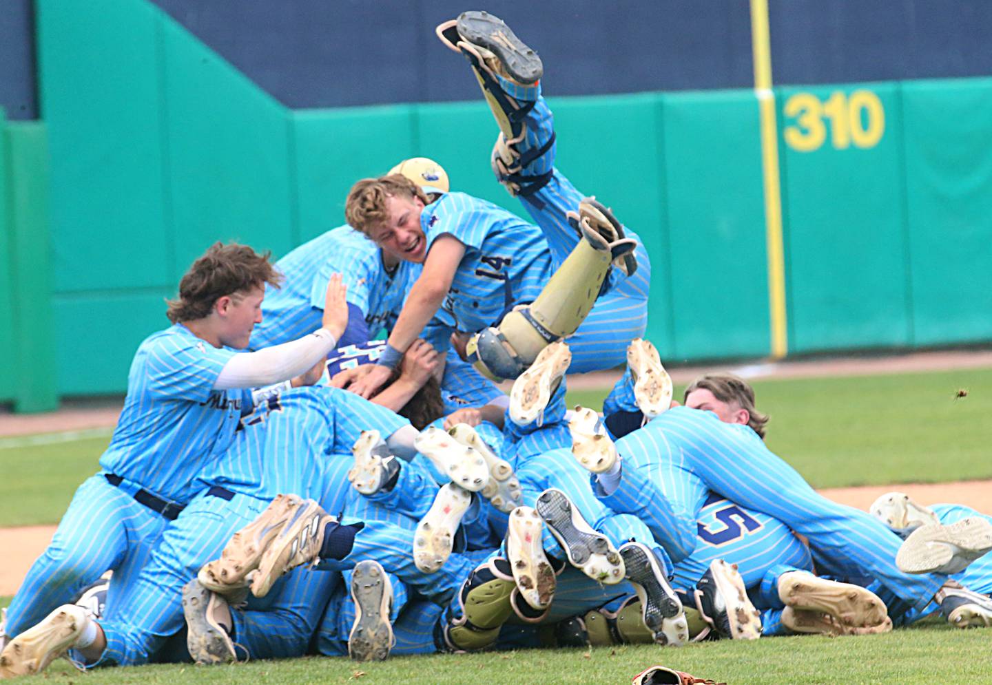Marquette's Billy Galyen (top) leaps on top of the pile of his teammates after the Crusaders defeated Altamont for the Class 1A state championship on Saturday, June 1, 2024 at Dozer Park in Peoria.