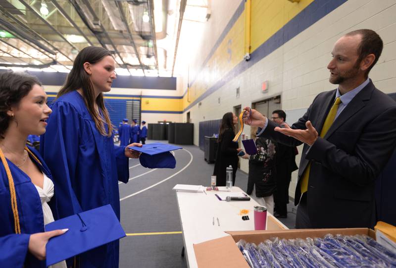 (left) Juliana Torres of LaGrange and Grace Turner of LaGrange Highlands receive a tassel from Lyons Township High School Assistant Principal Adam Davis prior to their graduation ceremony Wednesday May 29, 2024.