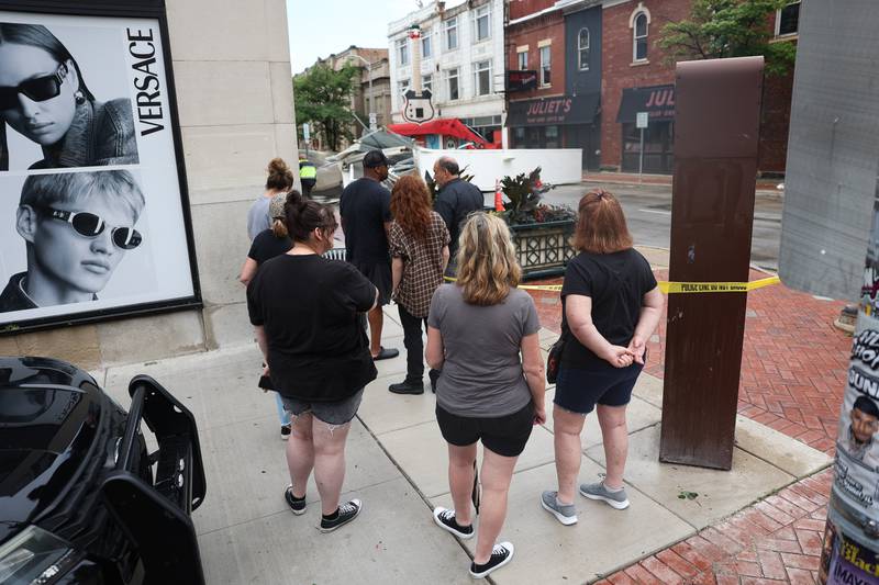 People gather at the corner of North Chicago Street and East Cass Street to see the damage after a storm blew through Joliet Sunday morning, July 14, 2024.