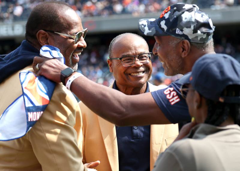 Members of the Chicago Bears 1985 Super Bowl champion team Richard Dent, (left) Mike Singletary and Otis Wilson (right) greet each other on the sidelines before the Bears meet the Tennessee Titans Sunday, Sept. 8, 2024, at Soldier Field in Chicago. Many players were on hand for a halftime celebration honoring new Hall of Fame Steve McMichael.