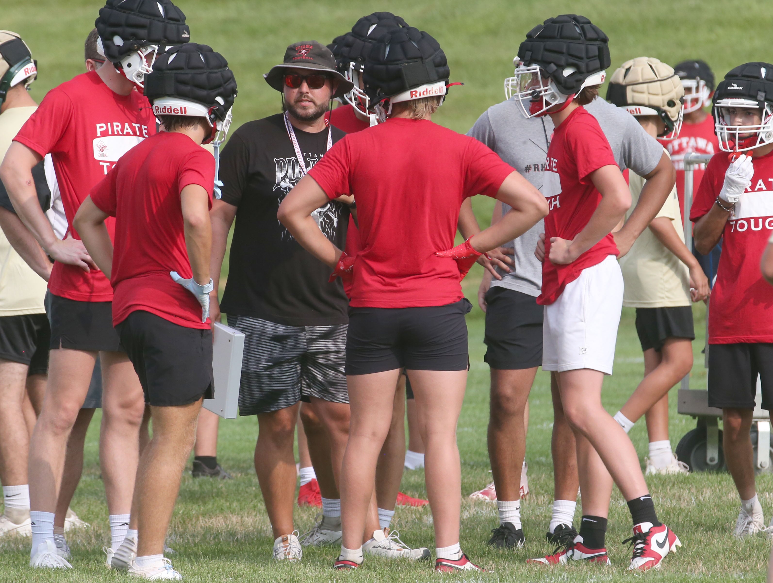 Ottawa football head coach Chad Gross huddles with his team whle playing St. Bede during a 7-on-7 meet on Wednesday, July 24, 2024 at Ottawa High School.