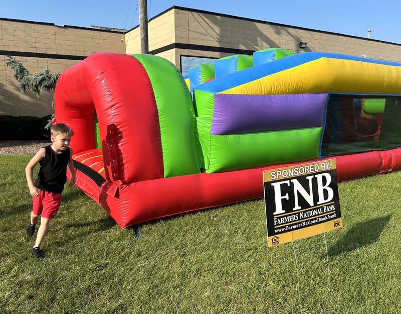 Mason Palumbo, 8, of Prophetstown runs through the inflatable obstacle course for kids at Prophetstown's Fourth Friday on Friday, July 26, 2024. Farmer's National Bank was one of the businesses that took part in the event.