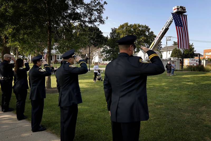 Firefighters salute as the flag is raised during a 9/11 remembrance ceremony on Sept. 11, 2024, at Veterans Park in McHenry.