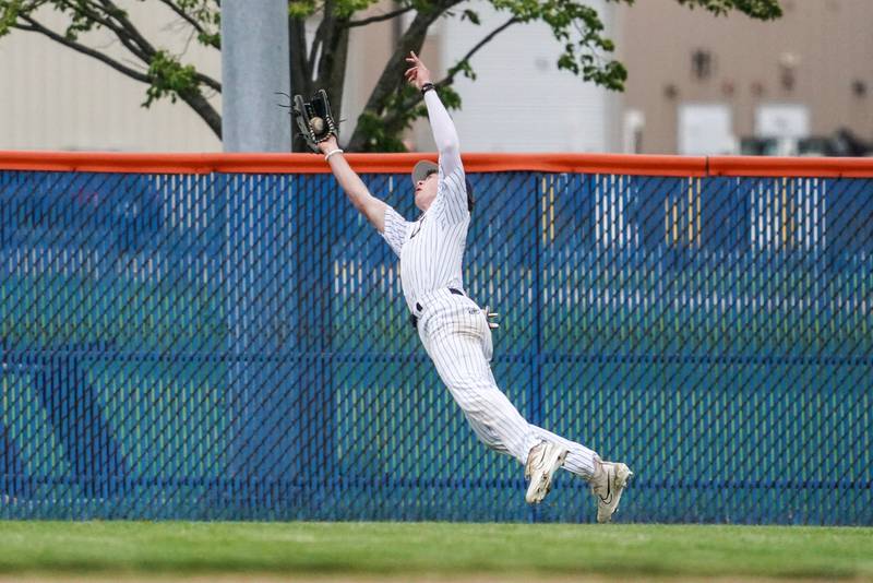 Oswego’s Jacob Fehrmann (18) makes a diving catch for an out against Oswego East during a baseball game at Oswego High School on Monday, May 13, 2024.