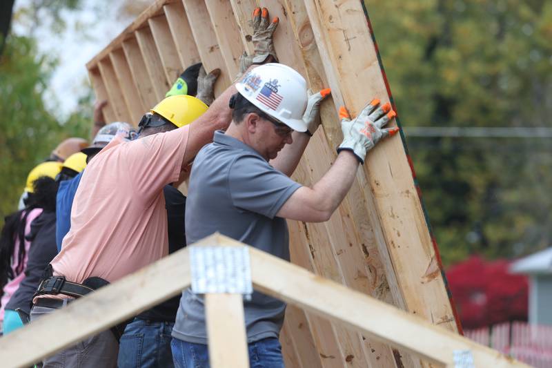 Volunteers put a wall frame in place of a home being built by Habitat for Humanity on Wednesday, Oct. 25, 2023 in Lockport.