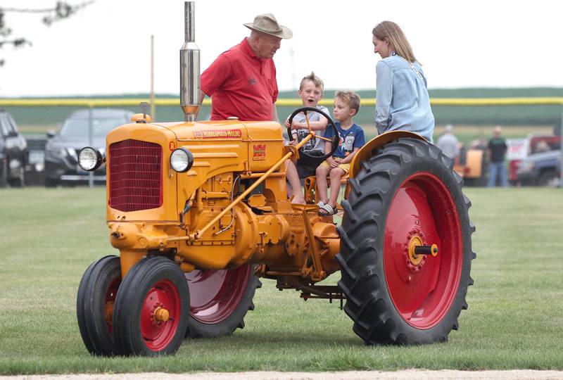 Emory Townsley, 7, (left) and his brother Myles, 3, from Waterman, get some help from their mom Nicole and Dan Cocher, director of the Northern Illinois Steampower Club, as they drive a vintage Minneapolis Moline tractor Saturday, July 16, 2022, at the Waterman Lions Summerfest and Antique Tractor and Truck Show at Waterman Lions Club Park.