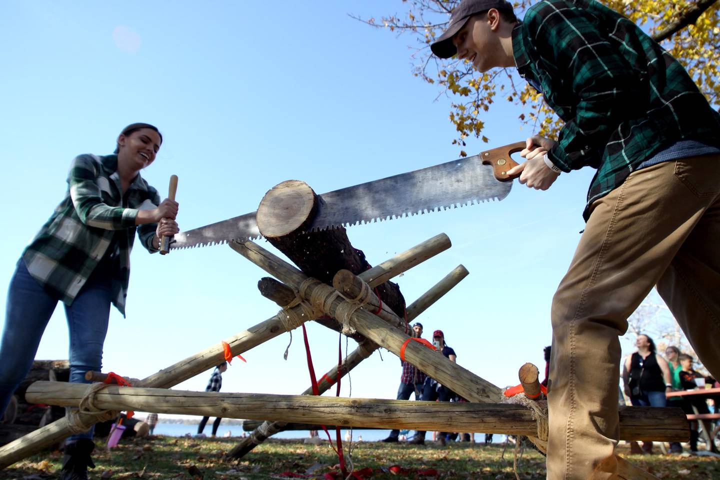 Grace Markovitz, left, of McHenry teams up with her boyfriend Ryan Peters of Wonder Lake to saw a log during the inaugural Flannel Fest at Crystal Lake’s Main Beach on Saturday.