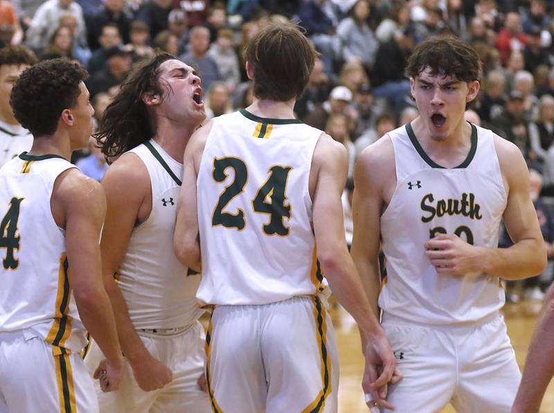 Crystal Lake South's AJ Demirov, (left) Michael Prokos (second from left) and Christopher Regillio (right) celebrate Crystal Lake South's James Carlson, three point play during the IHSA Class 3A Kaneland Boys Basketball Sectional championship game against Kaneland on Friday, March 1, 2024, at Kaneland High School in Maple Park.