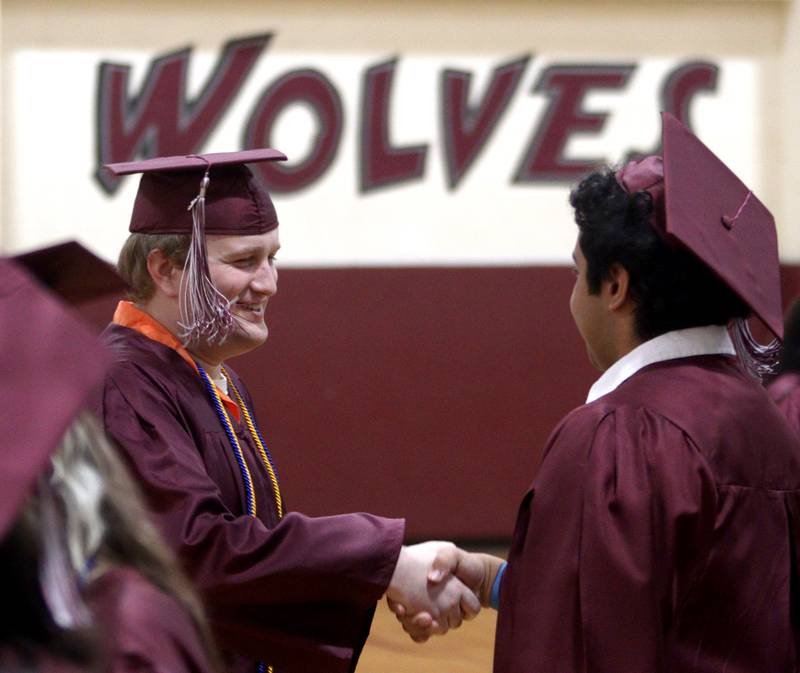 Jaxon Done, left, shakes hands with classmate Alfredo Benitez as they line up for Prairie Ridge High School commencement at the school in Crystal Lake on Saturday.