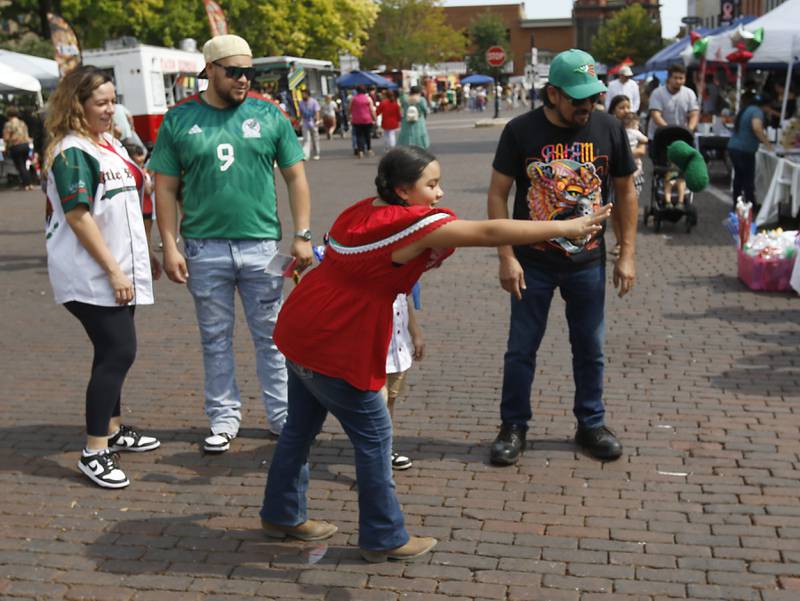 Kayls Loen tosses a pickle as tries to win a prize at the Claussen booth during the annual Hispanic Connections Mexican Independence Day Celebration on Sunday, Sept. 15, 2024, in the Historic Woodstock Square. The celebration featured music, food and culture.