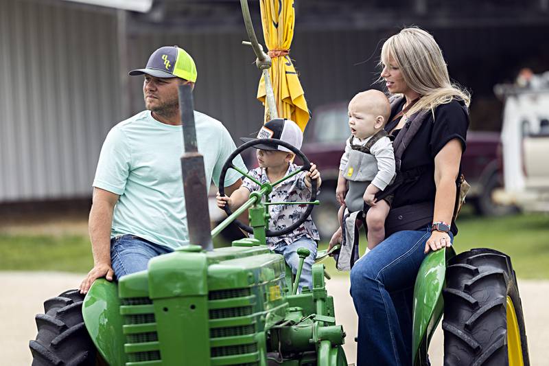 Rodee Kreiser, 3, steers his grandpa’s tractor with his family Lane, Oakley, 9 months and Jenna through the grounds Saturday, August 5, 2023 at the Living History Antique Equipment Association’s farm show in Franklin Grove.