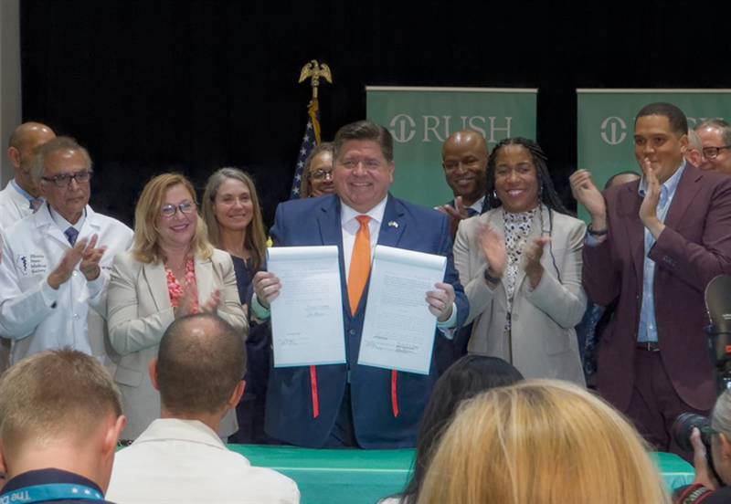 Gov. JB Pritzker holds up a pair of bills that were part of the Healthcare Protection Act, which he signed into law Wednesday at Rush University Medical Center in Chicago. Pritzker first outlined the insurance changes in his State of the State address in February.