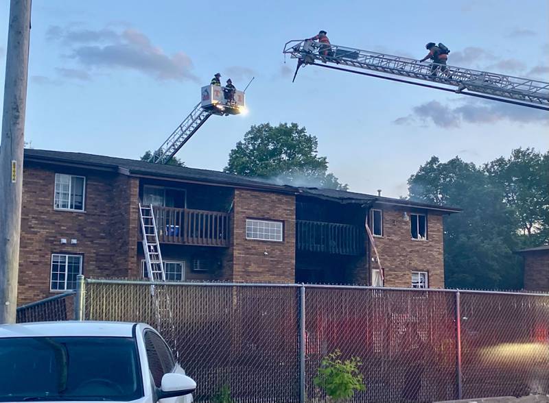 Firefighters from DeKalb and Rochelle work in tandem to staunch heavy smoke coming from the damaged roof responding to a structure fire at a Husky Ridge apartment complex in the 800 block of Kimberly Drive, DeKalb, on Wednesday evening, May 29, 2024.