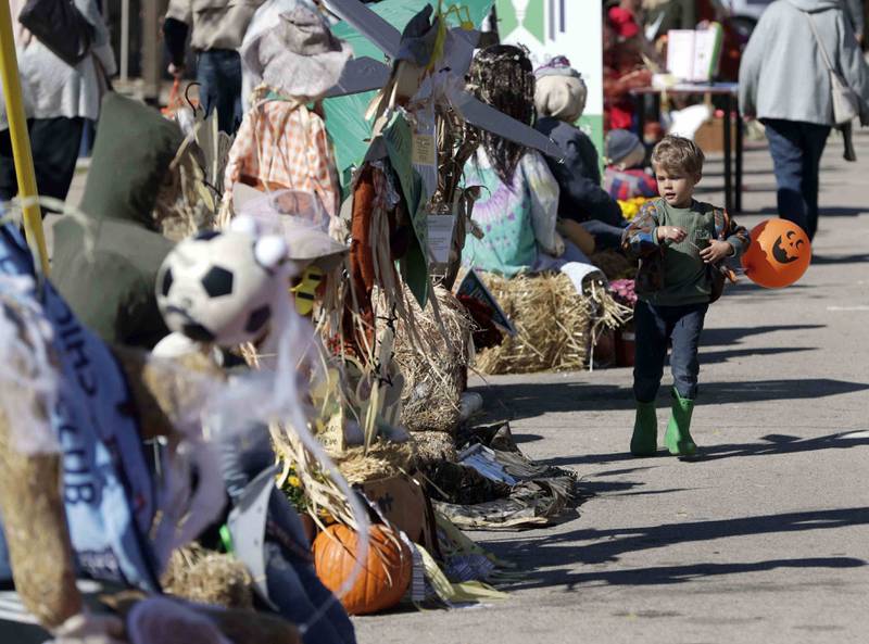 Four-year-old Ferin McKinley of St. Charles scurries past a row of scarecrows with his jack-o-lantern ballon during the opening day of Scarecrow Weekend Friday October 7, 2022 in St. Charles. The festival continues from 10 a.m. to 6 p.m. on Saturday and Sunday, Oct. 9, in downtown St. Charles. The 37th annual festival featuring 85 handcrafted scarecrows on display throughout downtown. Festivalgoers can vote to decide the winners in four categories: mechanical/mega; clubs, nonprofits and schools; individuals; and business. The family zone in Lincoln Park features live music and dance performances, magic show, giant bubble artist, a photo op area, scarecrow in a box and more. Plus, Touch-A-Truck, professional pumpkin carving and more. Autumn on the Fox Arts and Crafts Show is at Pottawatomie Park.