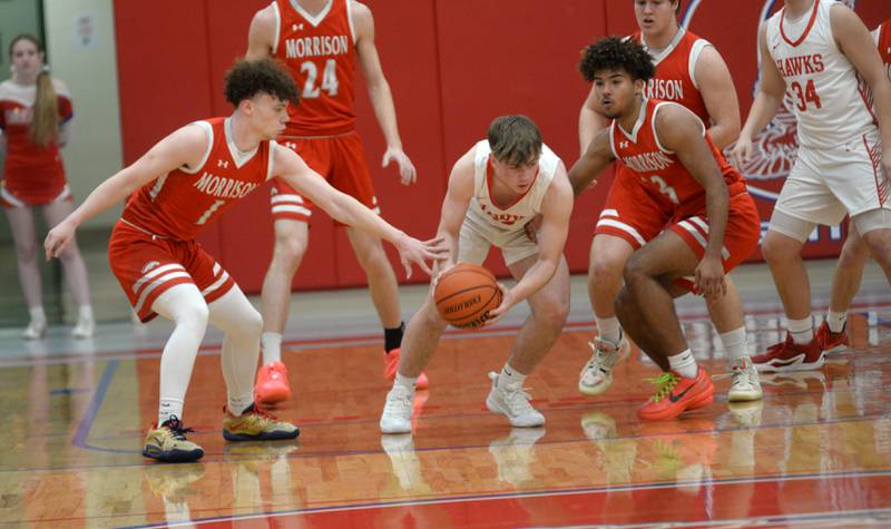 Oregon's Keaton Salsbury (center) dribbles out of a trap by Morrison's DaeShaun McQueen (right) and Dawson Hepner (left) during 2A regional action on Monday, Feb. 19, 2024 at the Blackhawk Center in Oregon. The Mustangs downed the Hawks 59-52.