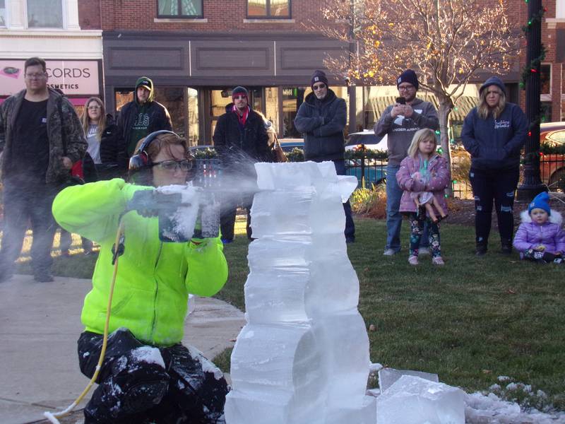 An ice sculptor creates a snowman out of a block of ice as spectators watch Saturday, Nov. 25, 2023, at Heritage Park in Streator as part of the Keeping Christmas Close to Home celebration.