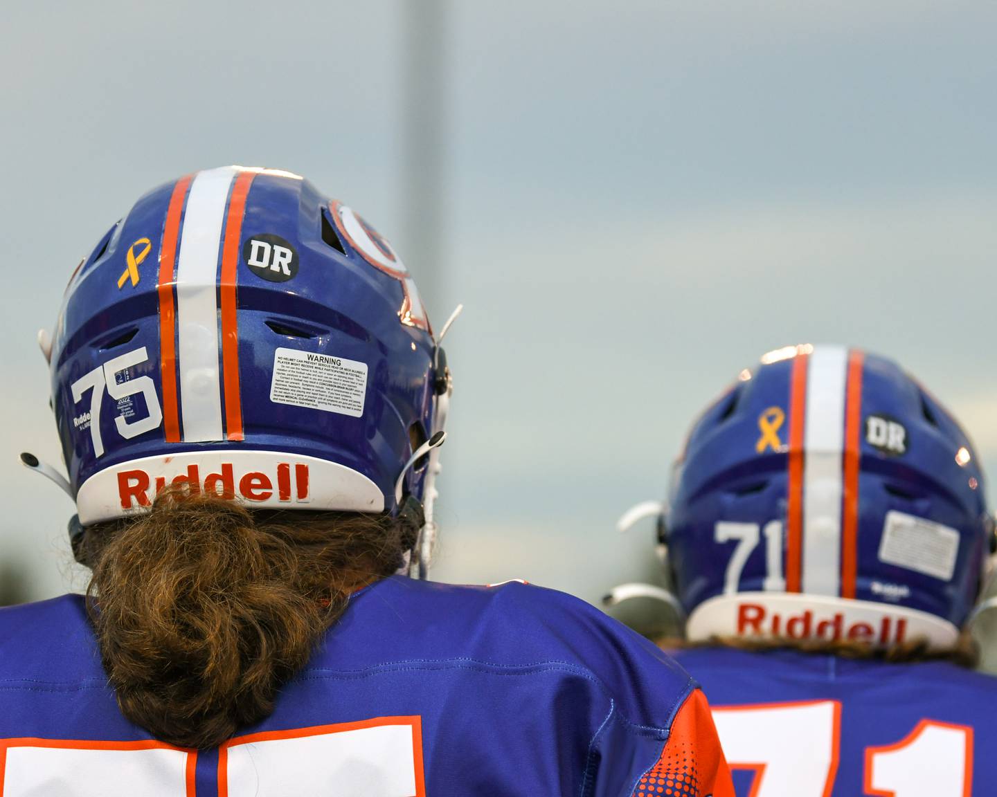 Genoa-Kingston players wear a DK sticker on their helmets on Friday Aug. 30, 2024, to honor former coach David Russell who passed away in December of 2023, who was honored during the first game of the season and a yellow ribbon for Kalista Breda a cheerleader who has cancer and will be honored during the second game of the season.