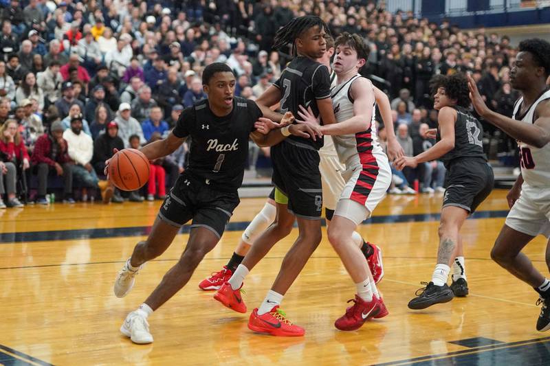 Oswego East's Andrew Wiggins (1) drives the baseline behind a pick from Mason Lockett IV (2) on Benet’s Patrick Walsh (4) during a Class 4A Oswego East regional final basketball game at Oswego East High School on Friday, Feb 23, 2024.