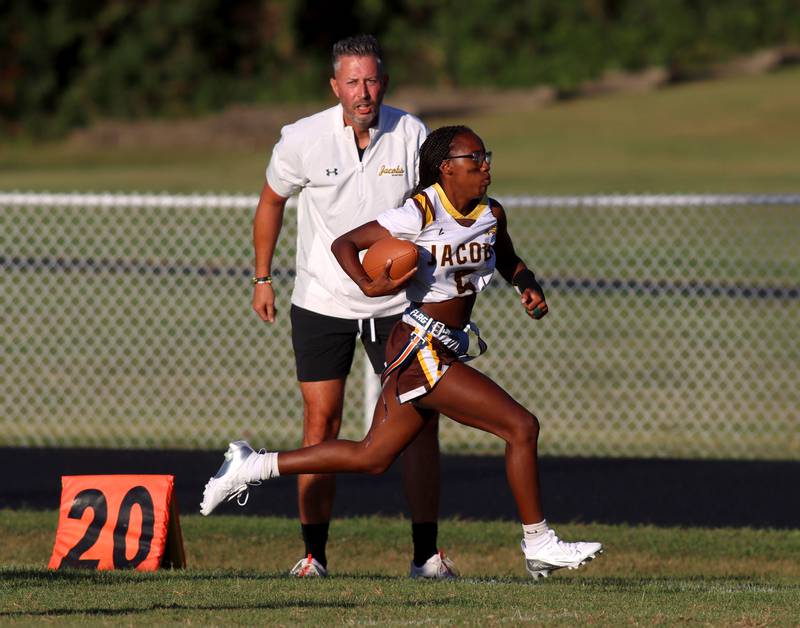 Jacobs’ Head Coach Jimmy Roberts shouts encouragement as Aaliyah Guichon hustles toward the end zone with a touchdown in varsity flag football on Tuesday, Sept. 3, 2024, at Dundee-Crown High School in Carpentersville.