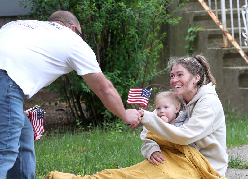 Lauryn Schultz and her daughter Via, 1, from DeKalb, receive a flag Monday, May 27, 2024, during the DeKalb Memorial Day parade on West Locust Street.