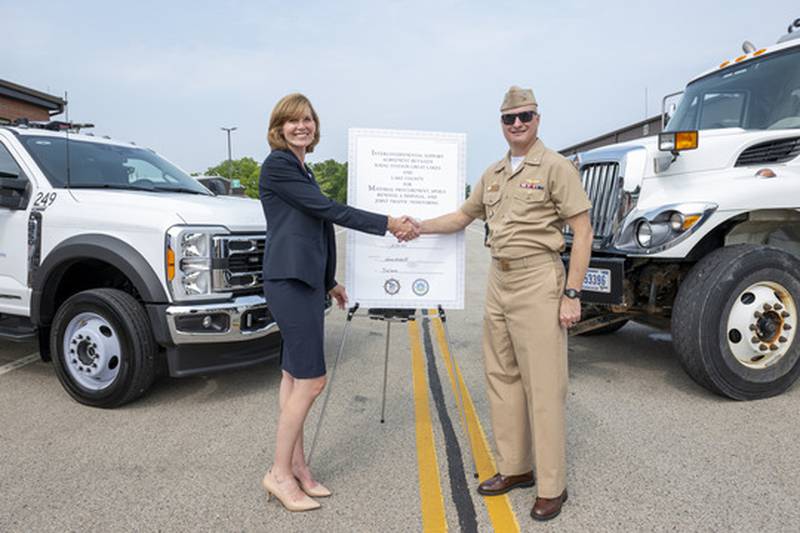 Sandy Hart, Lake County Board chair, and Capt. Steve Yargosz, commanding officer for Naval Station Great Lakes, shake hands at the ceremonial signing on July 23.