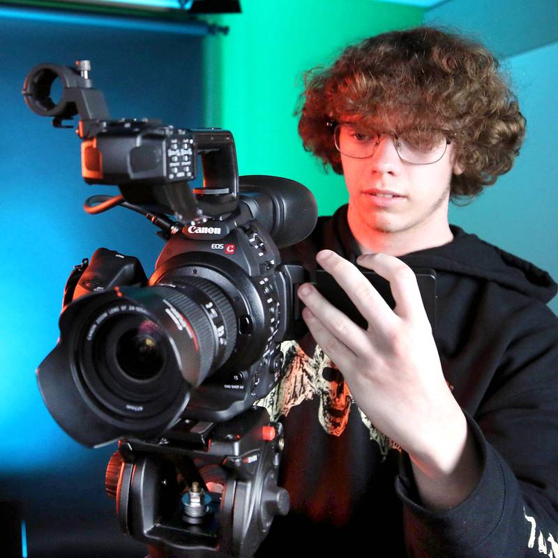 Johnny Howard, a junior at DeKalb High School, checks out a camera in the studio Thursday, March 7, 2024, at the school. Howard is part of the BarbCast network that broadcasts live streaming video of sports and events at the school as well as putting together promotional materials.