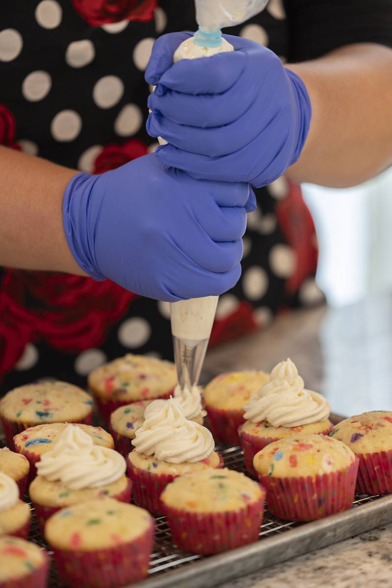 Christine Pomatto ices up confetti cupcakes Friday, July 19, 2024 in her home kitchen. Armed with over a hundred cookbooks, Pomatto has fine tuned her recipes.