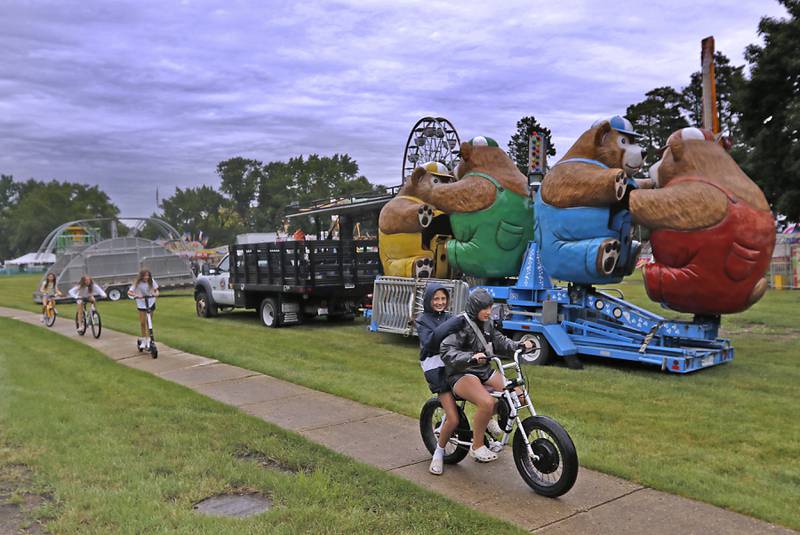 Girls ride past carnival rides waiting to be set up on Tuesday, July 2, 2024, for the Lakeside Festival at the Dole. The festival runs from July 4, through July 7.