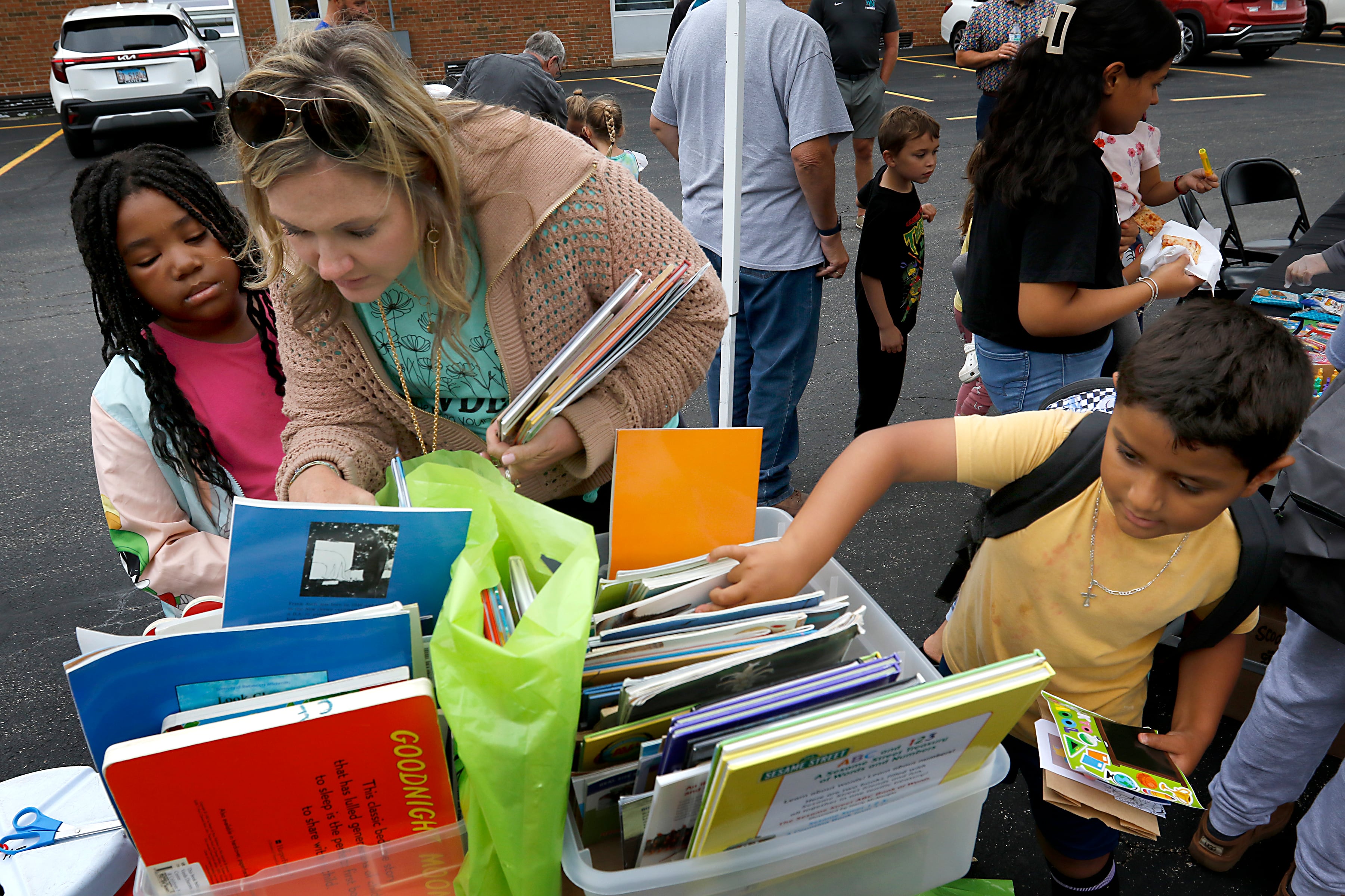 Suzanne Evenson helps JaKayla Ruffin find some books to read during a Woodstock School District 200 Back to School Coming to You event at Northwood Middle School on Tuesday, Aug. 6, 2024. The location was one of twelve stops on the tour that gave out backpacks and school supplies, provided registration help and computer repair.