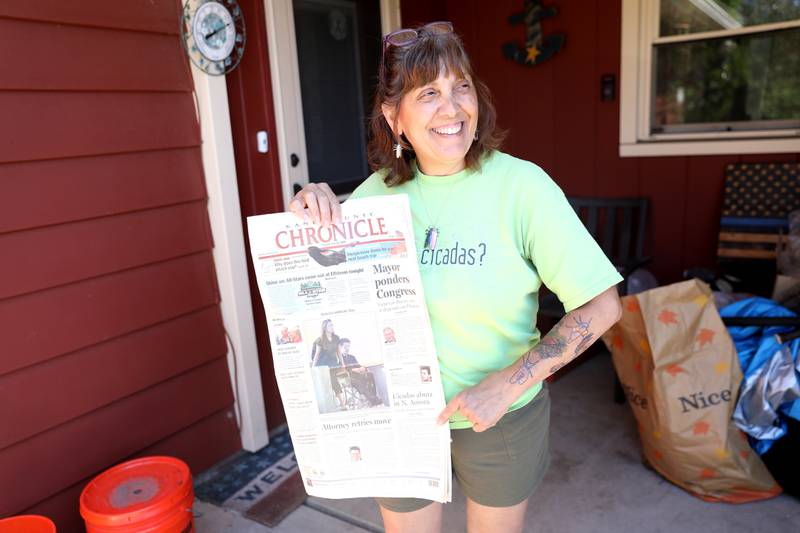 Bettina Sailer with the Kane County Chronicle newspaper from 17 years ago, when she first attempted to rehome cicadas in the yard of her North Aurora home. With her yard facing a similar lack of cicadas this year, she has been doing the same thing and now has more than 4,000 cicadas in her yard.