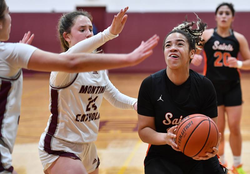 St. Charles East's Corinne Reed (right) goes for the basket while double teamed by Montini's Peyton Farrell (24) and Alyssa Epps during the Montini Christmas Tournament championship game on Dec. 29, 2023 at Montini Catholic High School in Lombard.