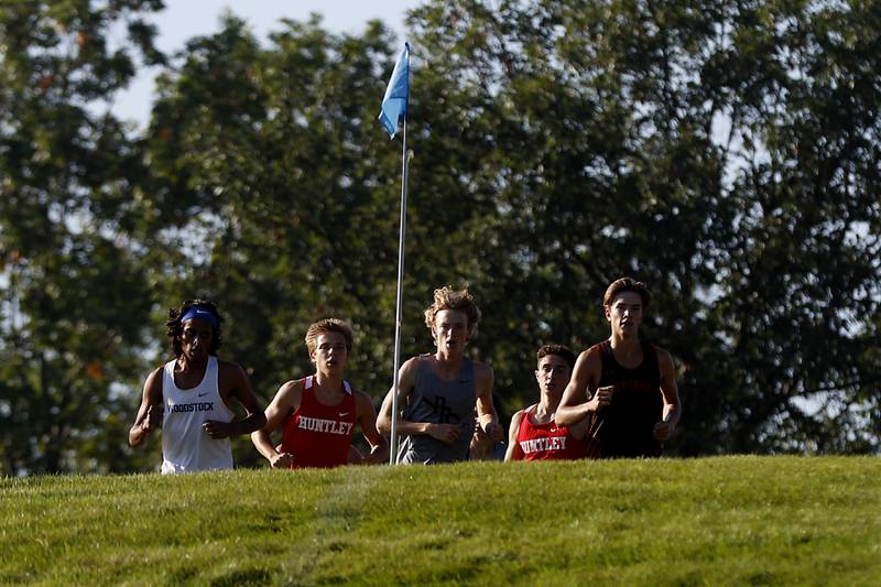 Woodstock’s Ishan Patel, Huntley’s Tommy Nitz, Prairie Ridge’s Will Gelon, Huntley’s Ty Rasmussen, and Crystal Lake Central’s Karson Hollander crest a hill as they compete in the boys race of the McHenry County Cross Country Meet Saturday, August 27, 2022, at Emricson Park in Woodstock.