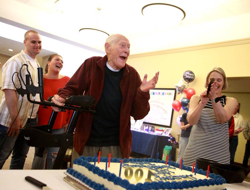 Bob Larson laughs with family and friends after blowing out the candles on his birthday cake for his 100th birthday celebration at Covenant Living at the Holmstad in Batavia on Wednesday, May 29, 2024. Larson was in the Navy on the USS Texas when the ship was assigned to Omaha Beach on D-Day to do bombardment of Normandy to support the Allied invasion in World War II.