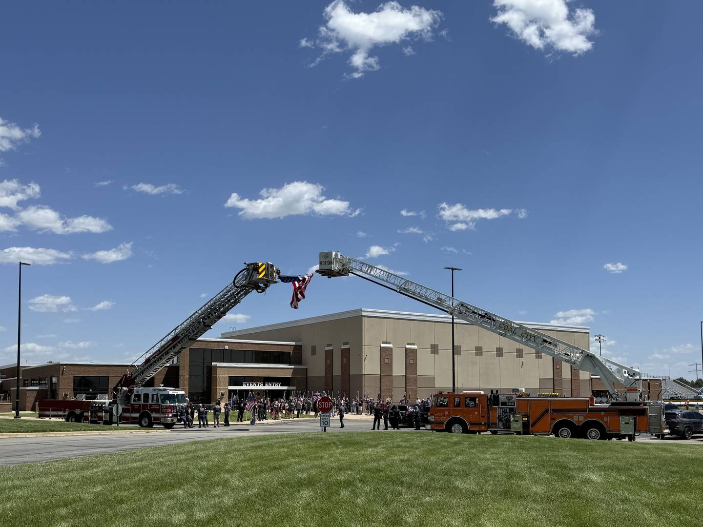 Family and friends hold flags while a large one blows in the wind during the deployment ceremony held in Coal City on Thursday for Bravo Company 766.