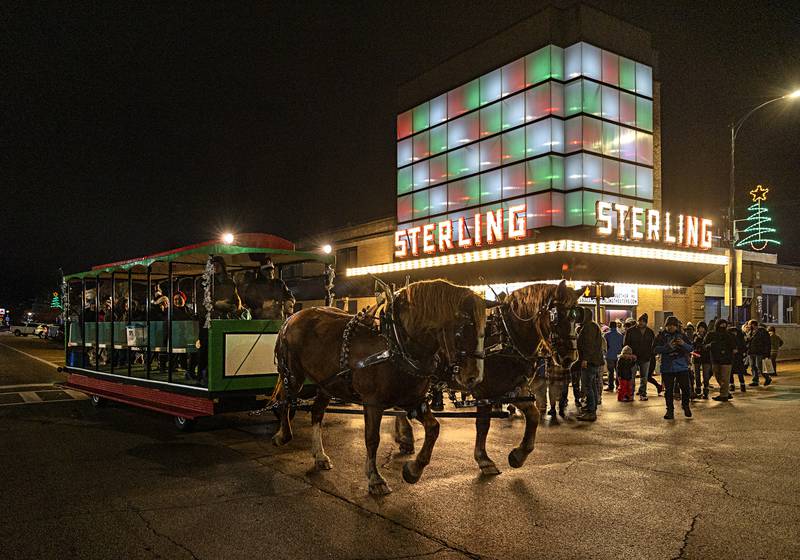 A horse drawn carriage moves past the Sterling theater Friday, Dec. 1, 2023 as revelers take a ride through the downtown for the Seasonal Sights and Sounds Christmas walk.