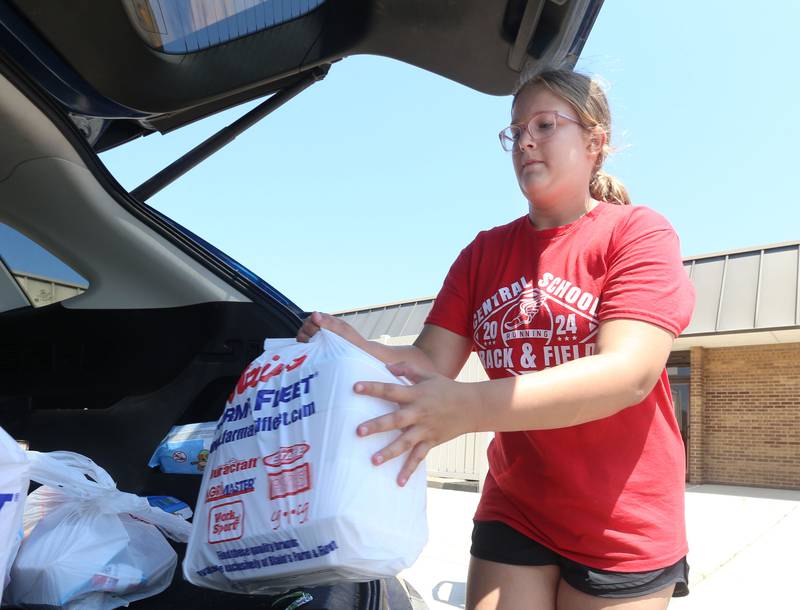 Ella Waddell fills a bag full of food inside the trunk of a vehicle outside of Sheppard Middle School on Wednesday, July 17, 2024 in Ottawa. The Summer Meal program provides two meals per day. The program is held every Wednesday from 10a.m.-1p.m. at the school. You must order the meal bags by clicking on the links posted on the Shepard Middle School Facebook page.