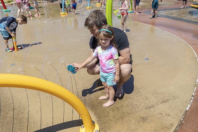 Jesse Slowikowski helps daughter Maya, 2, play with the water at the Dixon Park District splash pad Wednesday, June 12, 2024. A heat wave is poised to make the pad a popular place.