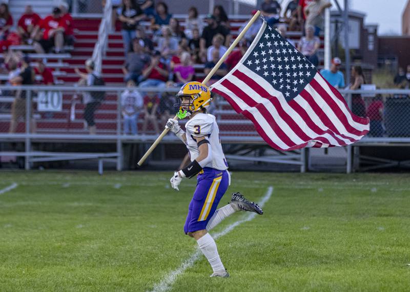 Mendota's Rhett Watson runs out onto the field with an American flag prior to the start of the Hall-Mendota football game at Richard Nesti Stadium on September 13, 2024.