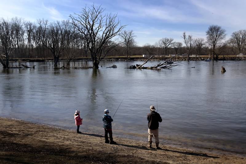 A father and his children fish on Wednesday, Feb. 14, 2024, at the McHenry Dam.