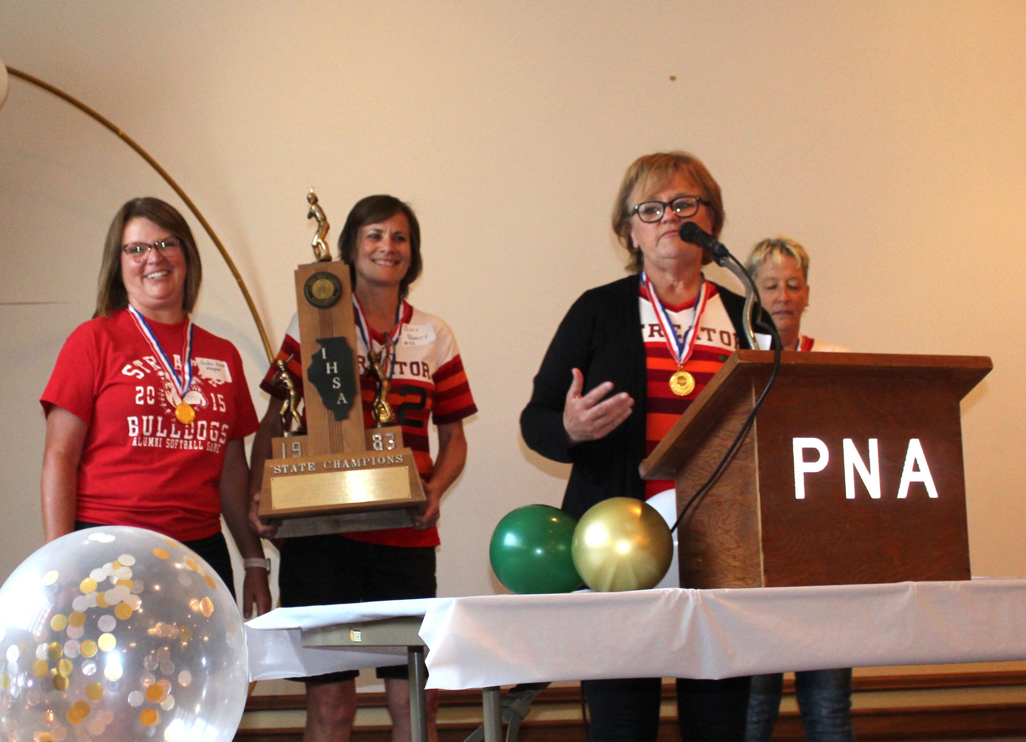 Zami (Mogill) Hay addresses the crowd as fellow 1983 Streator softball all-tournament selections (left to right) LuAnn (Kozak) Wagner, Amy (Pedelty) Ferko and Linda Weiss share the stage at the Night of Champions event Saturday, June 10, 2023, at the Streator PNA Hall marking the 40th anniversary of the team’s state championship.