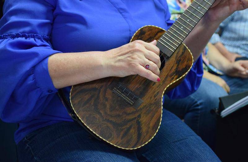 Sue Klopfenstein of Wild Blue Ukulele Orchestra strums during a performance at Ax in Hand in DeKalb on May 29.