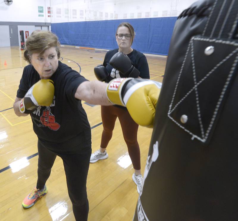 Elaine McKinney extends punches a bag during her Rocksteady Boxing class at the Streator YMCA with instructor Nichole Reynolds alongside her.