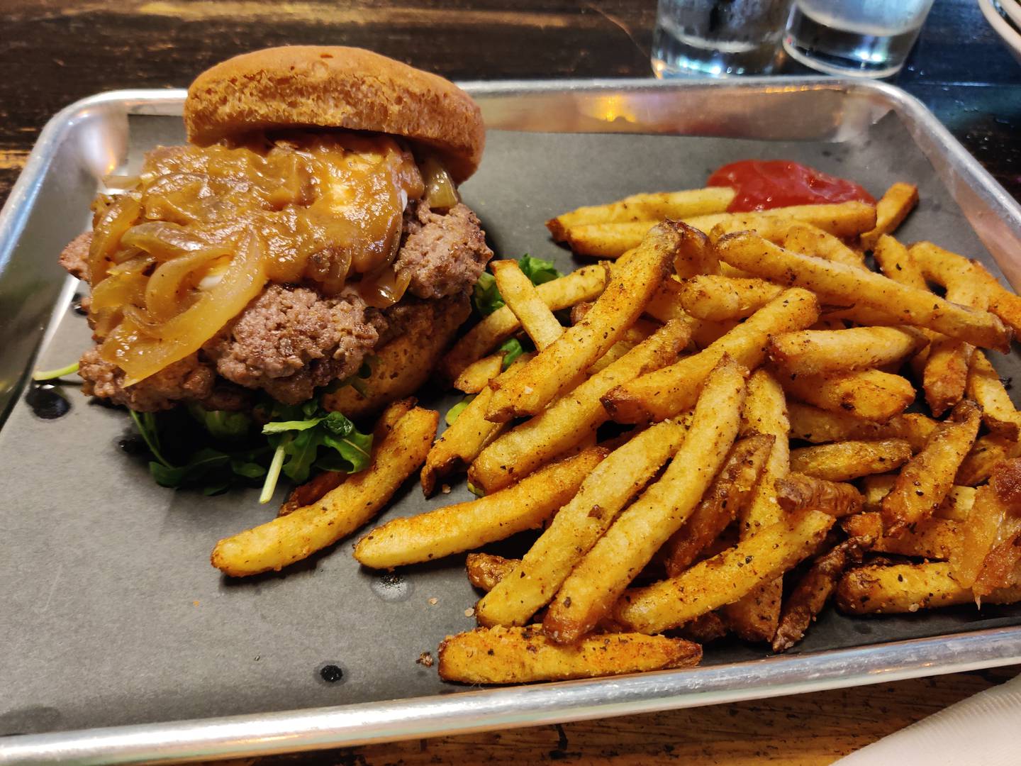 The GOAT, and noticed we appropriately were seated under a joyful closeup of Michael Jordan celebrating a championship win.
Two side-by-side smashed patties arrived with herbed goat cheese, grilled onions, fig jam and arugula. I was able to order a tasty gluten-free bun instead of the brioche. The fig jam lent an earthy sweetness to the burger in a nice interplay with the tangy goat cheese at The GOAT burger + cocktail bar in Batavia